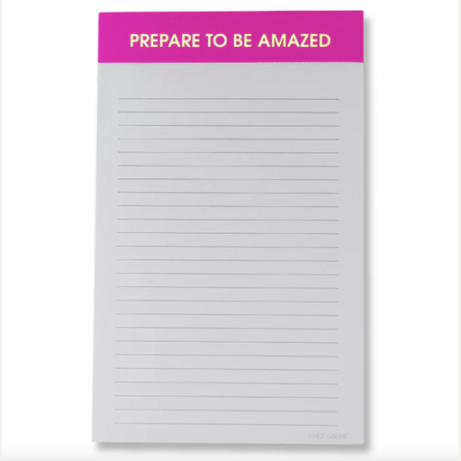 Stationery by Chez Gagné featuring a centered lined notepad with a vibrant hot pink header containing the gold-lettered phrase PREPARE TO BE AMAZED and thin gray horizontal lines on a light background