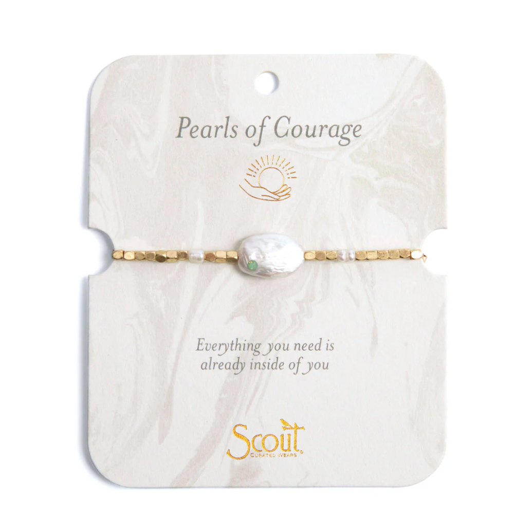 Jewelry by Scout Curated Wears featuring a Pearls of Courage bracelet centered on a marble-patterned card, showcasing a large iridescent baroque pearl with a tiny green inset stone and gold-toned faceted beads