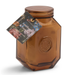 Studio photograph by Paddywax of a Leather and Smoke soy wax candle in an amber-tinted hexagonal glass jar featuring an embossed P seal and a vibrant floral hangtag against a plain white background