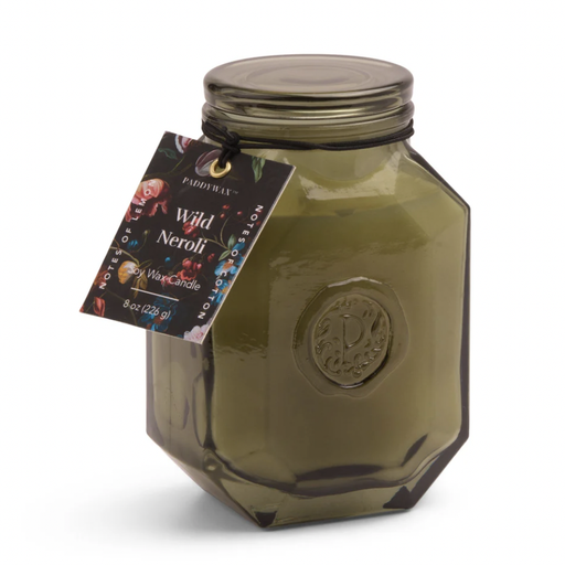 Soy wax candle by Paddywax featuring the Wild Neroli fragrance in a faceted olive green glass jar with an embossed P seal, a matching glass lid, and a colorful floral tag against a white studio background