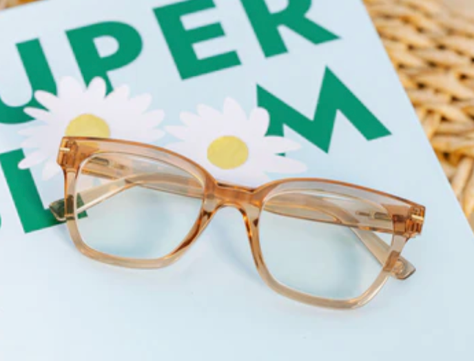 Translucent tan glasses resting on a magazine with daisies on the cover