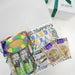 Mardi Gras-themed gift set with a card and decorative items on a white background