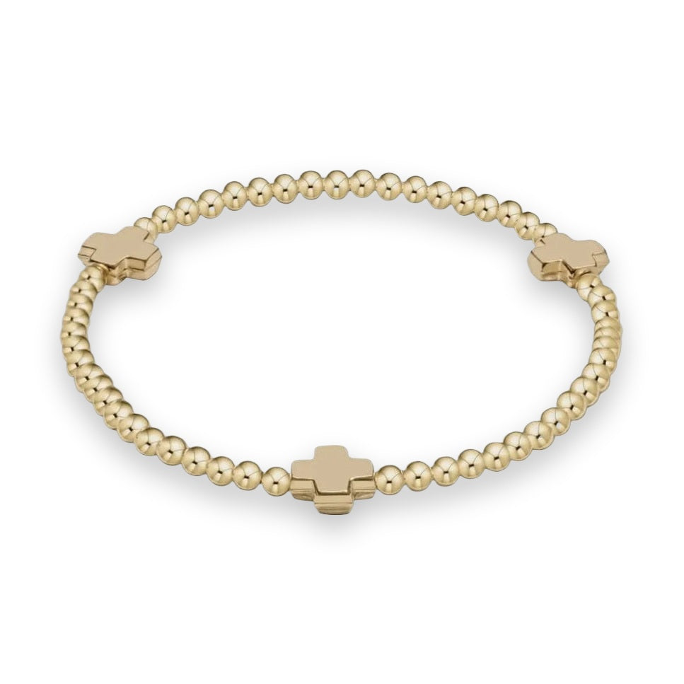 Yellow gold beaded bracelet by Ferragamo featuring three signature cross-shaped charms and small polished spherical beads against a neutral background