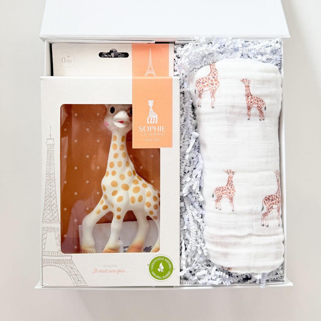 Baby gift set with a giraffe toy and diapers in a box on a white background