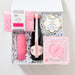 Set of beauty products including a pink lip balm, black nail file, and other items in a clear box on a white background.