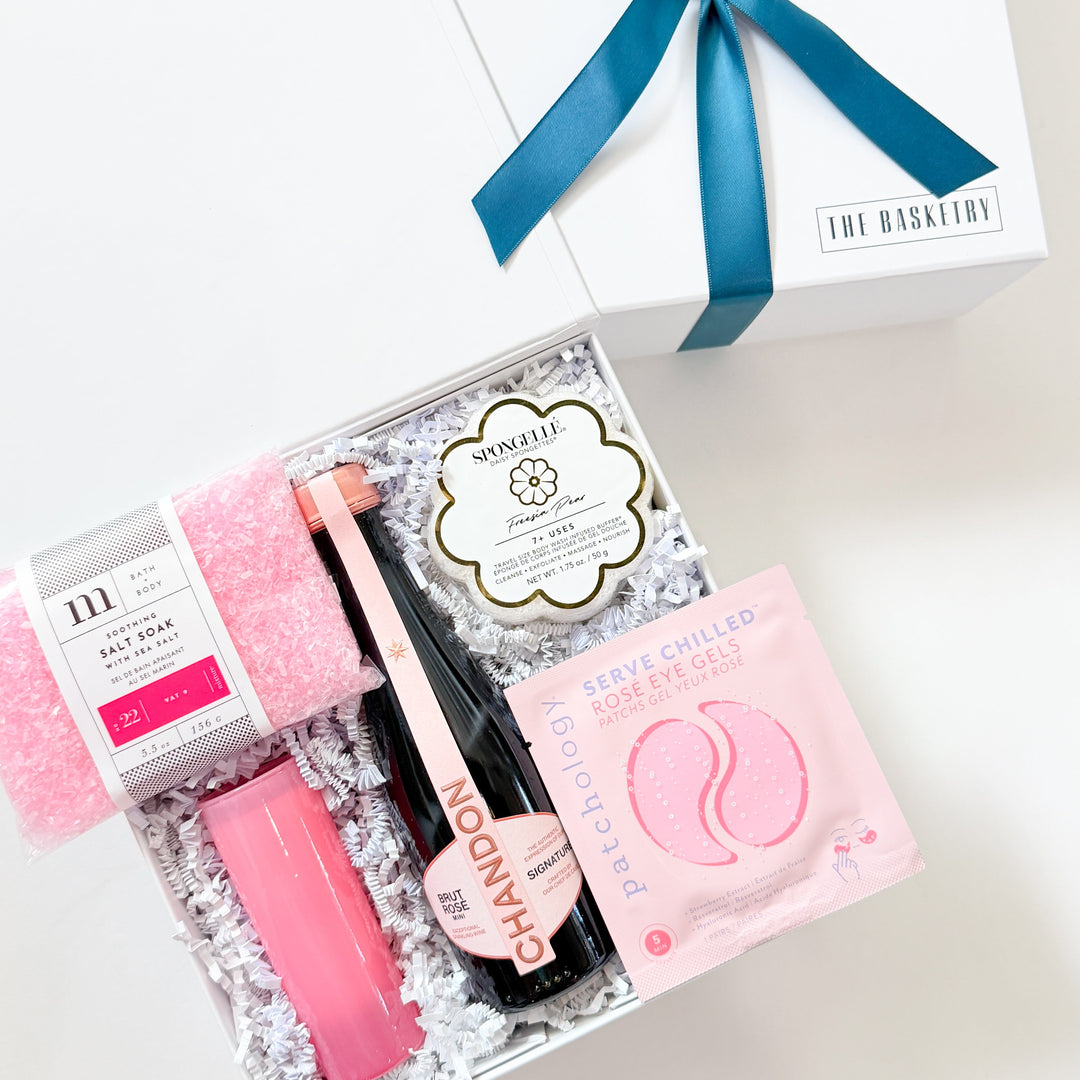 Gift set with pink and black items and a blue ribbon on a white background