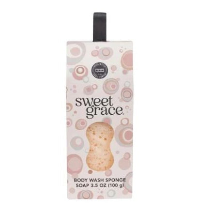 Product packaging by Bridgewater Candle Company for the Sweet Grace Body Wash Sponge soap featuring a pink and beige circular bubble pattern, a black fabric hanging strap, and an hourglass-shaped window revealing the textured sponge inside