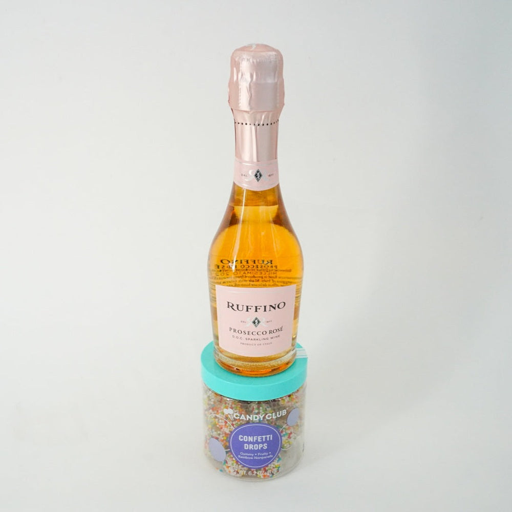 Miniature bottle of Buffino Prosecco with a small container of sprinkles on a white background