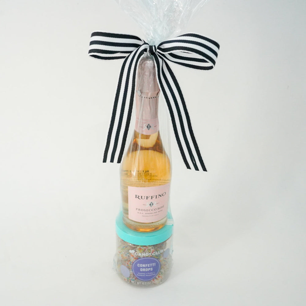 Bottle of champagne with a black and white striped bow on a white background