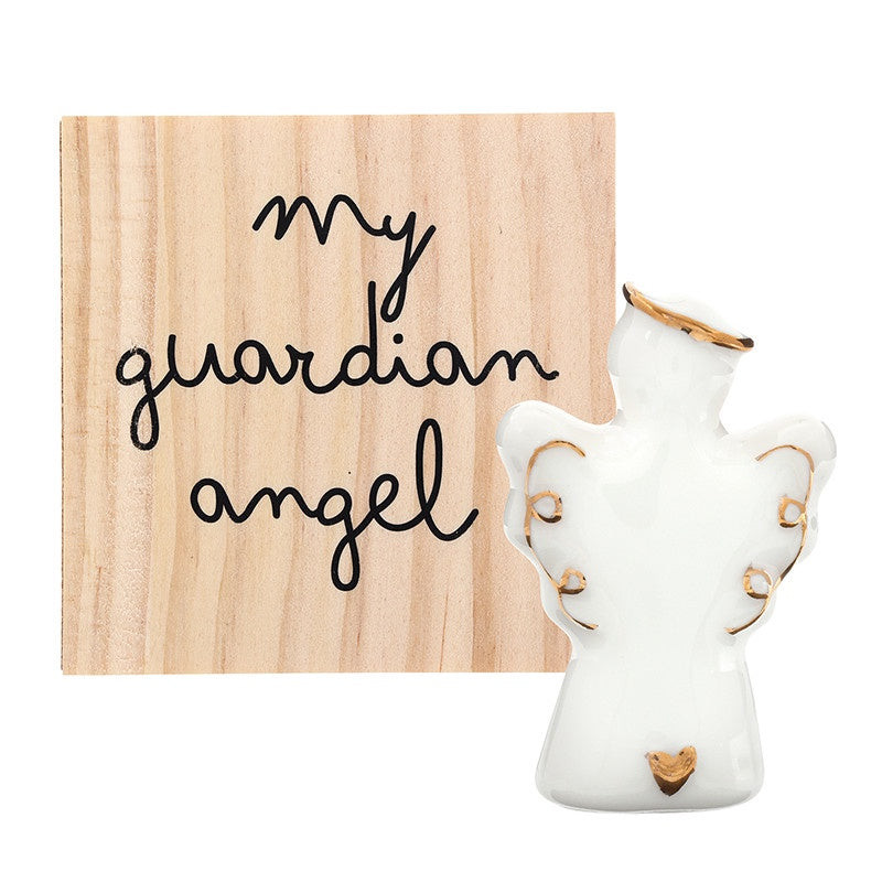 Ceramic and wood decorative set featuring a small white glazed angel with a gold-rimmed halo and tiny gold heart standing beside a square wooden block printed with the words my guardian angel in black cursive script against a plain white background