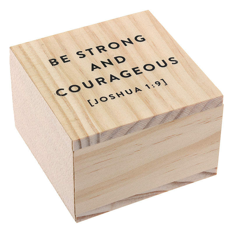 Small pine wood box featuring the black sans-serif typography BE STRONG AND COURAGEOUS JOSHUA 1:9 on its lid, showcasing natural wood grain textures and a minimalist square silhouette against a solid white background