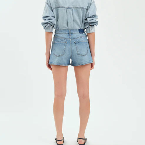 Back view of light wash high-rise denim shorts worn with a chambray shirt