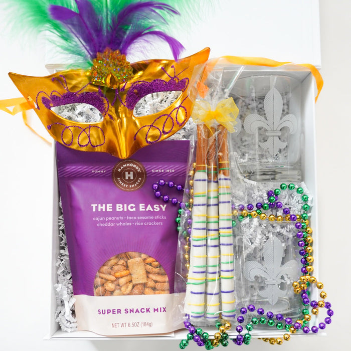 Mardi Gras-themed gift set with a mask, beads, and snack mix on a white background