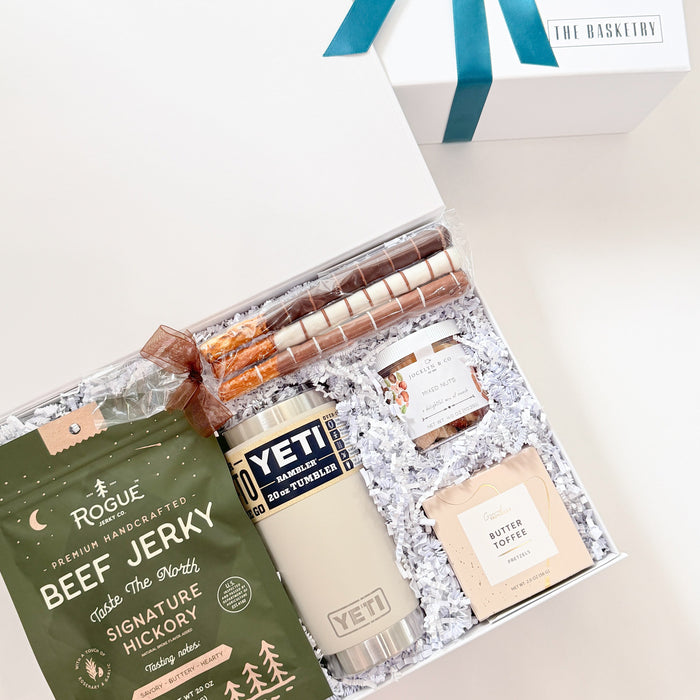 Gift set with beef jerky, Yeti mug, and other items on a white background