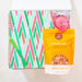 Notebook with colorful zigzag pattern, pink candle, and snack mix on a white background
