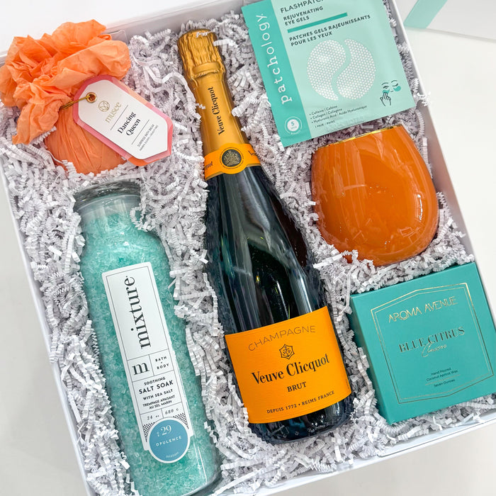 Gift set with champagne, bottle of mixer, and decorative items in a box.