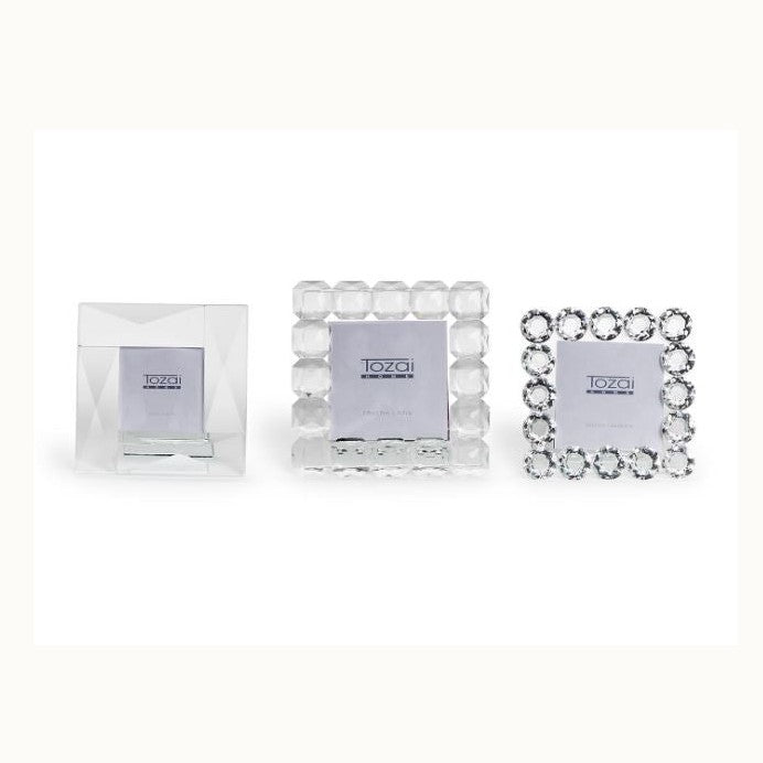 Crystal and glass frames by Tozai Home featuring three square decorative frames on a white studio background with a beveled geometric design, chunky faceted crystal beads, and a border of round brilliant-cut gems