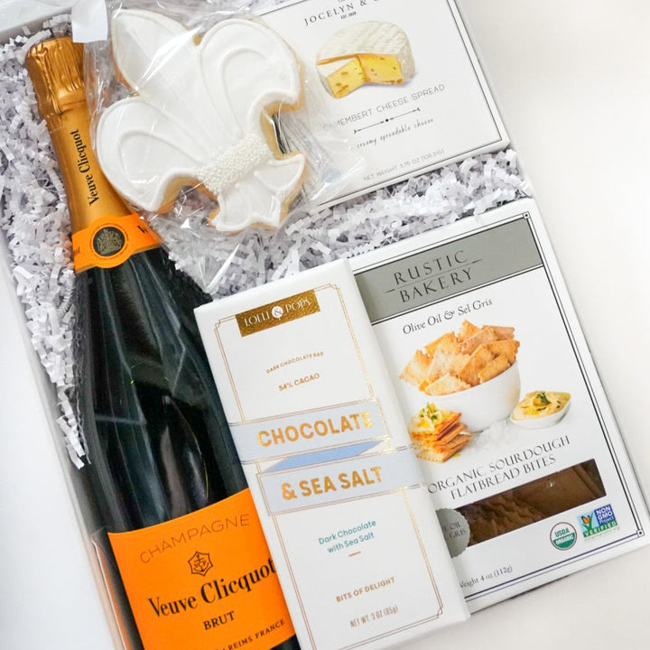 Gift set with champagne bottle, cookies, and chocolate bars on a white surface