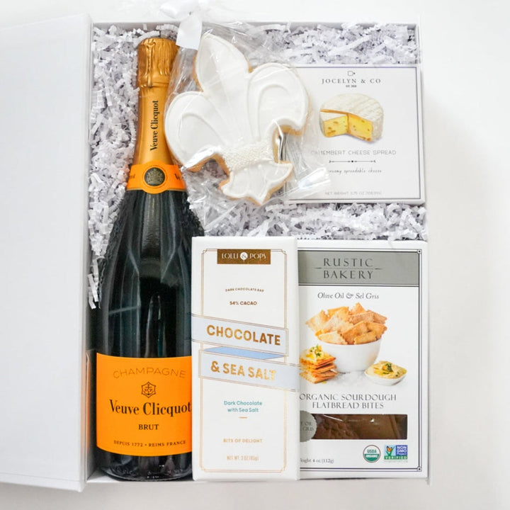 Gift box with a bottle of Veuve Clicquot, chocolate bars, and cookies on a white background