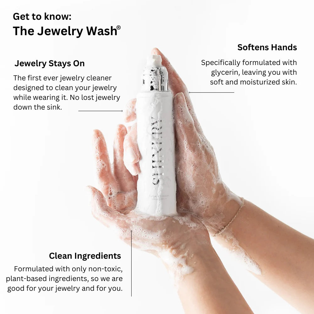 Commercial product photography by Shinery featuring hands covered in white foamy lather holding an embossed bottle of The Jewelry Wash against a white background while wearing a delicate gold chain bracelet