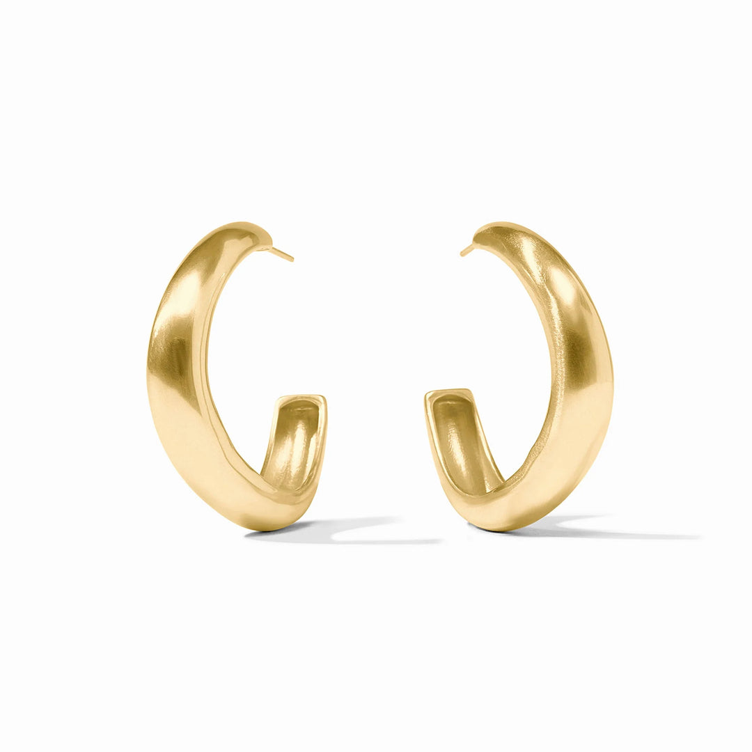 Brushed gold jewelry photography of a pair of thick hoop earrings on a white studio background showcasing a prominent C-shaped silhouette with a matte satin finish and smooth tapered ends