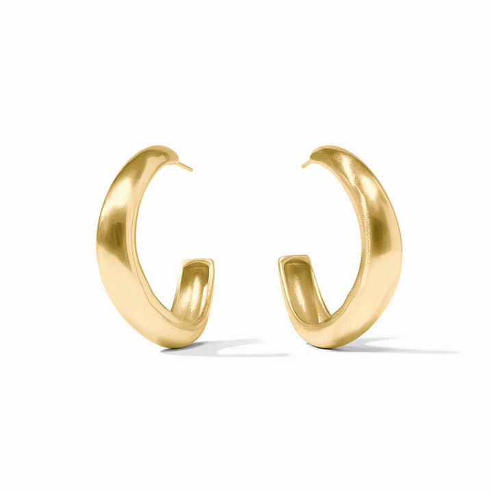 Brushed gold jewelry photography of a pair of thick hoop earrings on a white studio background showcasing a prominent C-shaped silhouette with a matte satin finish and smooth tapered ends