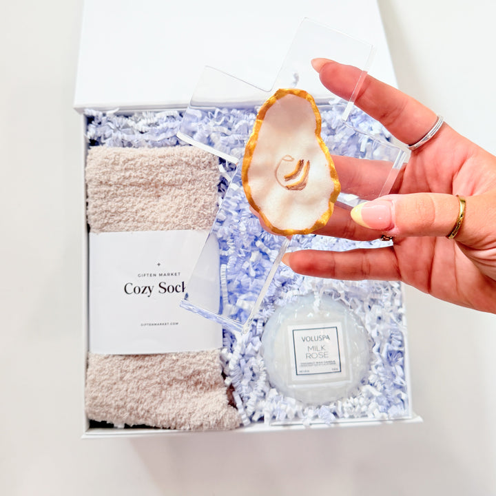 Hand holding a bath product set with a towel and loofah on a white background
