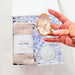 Hand holding a bath product set with a towel and loofah on a white background