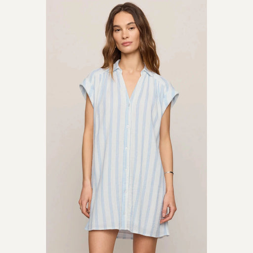 Woman wearing a light blue striped dress against a beige background