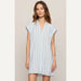 Woman wearing a light blue striped dress against a beige background