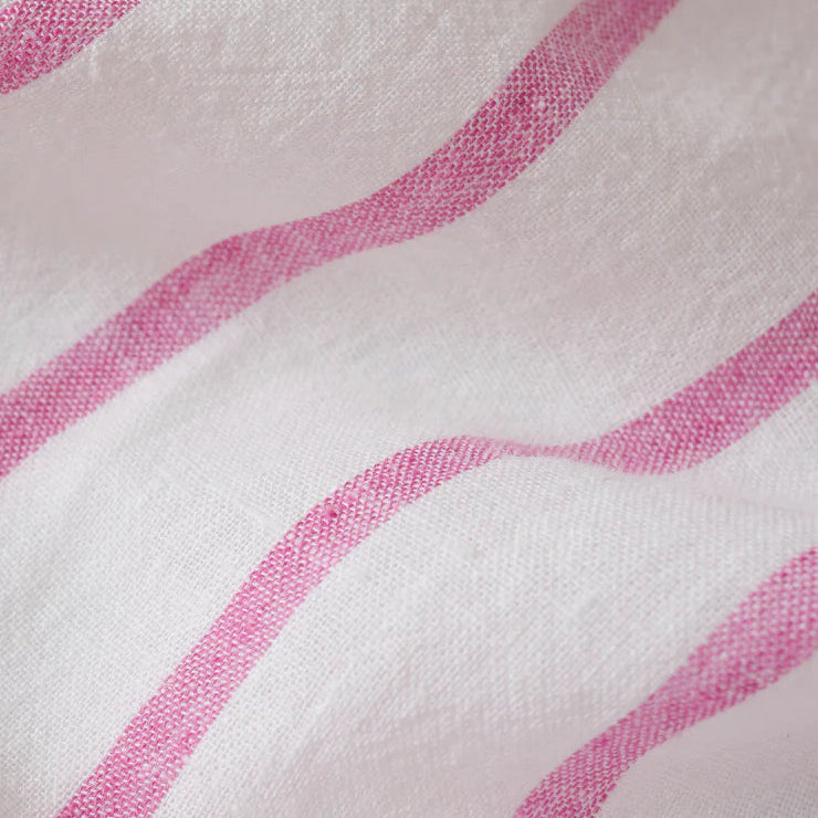 Close-up photograph of textured white linen fabric featuring vibrant pink stripes with a visible weave and soft ripples in the material