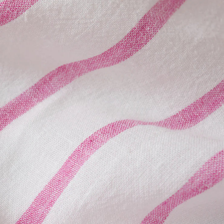 Close-up photograph of textured white linen fabric featuring vibrant pink stripes with a visible weave and soft ripples in the material