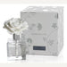 Porcelain air diffuser by The White Company featuring a blooming white ceramic gardenia topper and clear square glass bottle displayed next to a silver floral-patterned Seychelles gift box