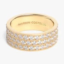Gold-toned jewelry by Marrin Costello featuring a wide band encrusted with three rows of brilliant pavé crystals and an interior brand engraving on a plain white background