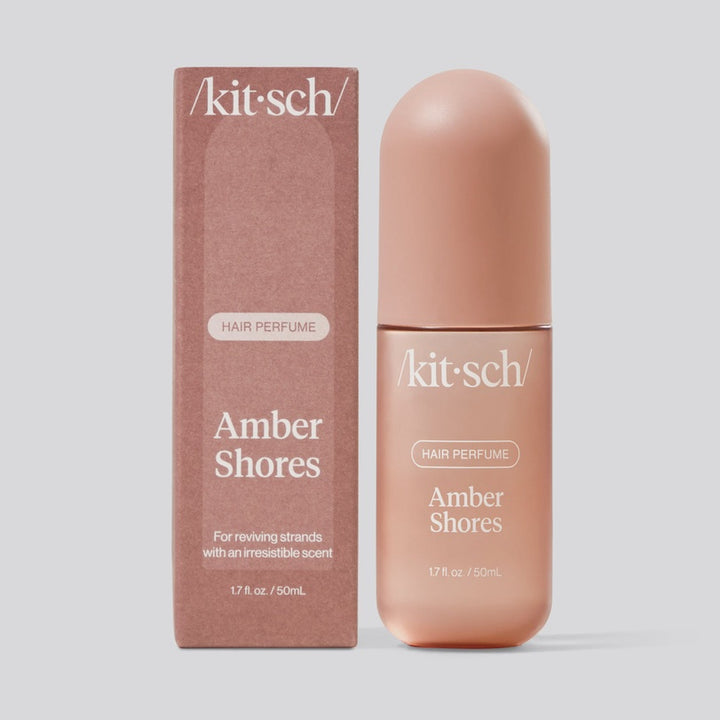 Studio product photograph of Kitsch Amber Shores Hair Perfume showcasing a textured terracotta-colored box beside a matching 1.7 ounce bottle with a distinctive rounded matte cap against a minimal grey background