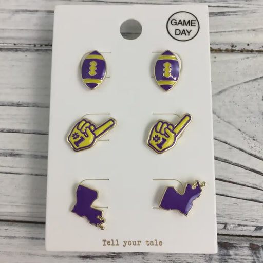 Enamel stud earrings by Tell your tale featuring purple and gold footballs, number one foam fingers, and Louisiana state map silhouettes on a white Game Day display card
