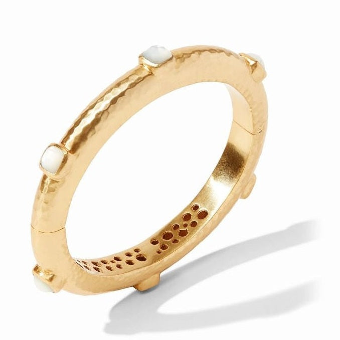 Hammered gold jewelry by Ippolita featuring a hinged bangle bracelet with luminous square mother-of-pearl stations and a decorative circular cutout pattern on the interior rim against a white background