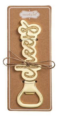Gold-plated metal bottle opener by Mud Pie featuring cursive Cheers script with shimmering gold glitter inlay mounted on a kraft paper card and tied with a rustic jute twine bow
