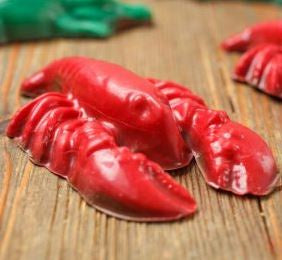 Red candy-coated chocolate crawfish on a wooden table