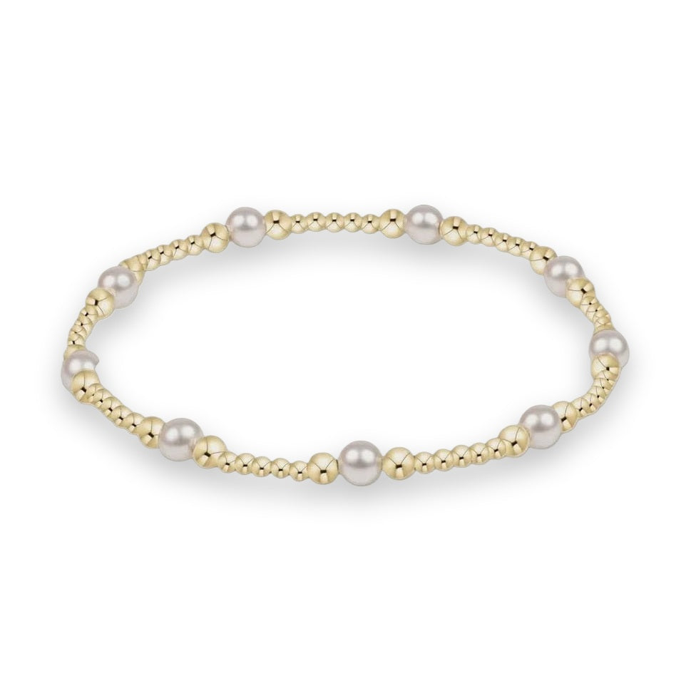 18K yellow gold and freshwater pearl bracelet by Lagos featuring signature Caviar beadwork and graduated luminous white pearls against a neutral grey studio background