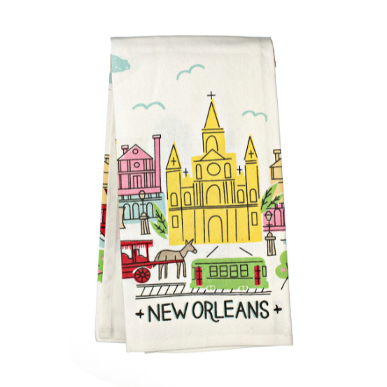 Screen-printed illustration by Cat Studio on a white tea towel featuring New Orleans landmarks including the yellow St. Louis Cathedral, a green streetcar, and a red mule-drawn carriage with pink townhouses and teal clouds