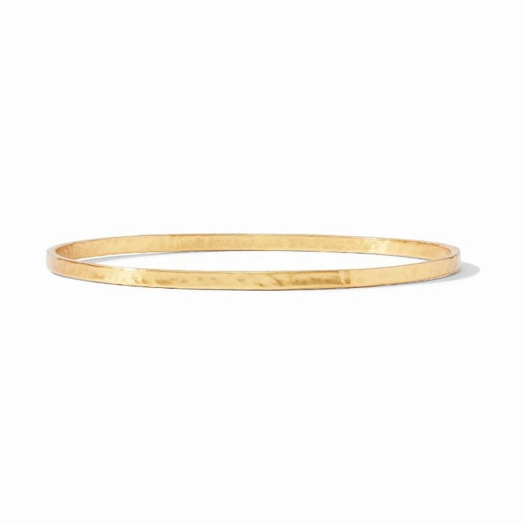 Hammered 18k gold-plated brass jewelry showcasing a minimalist thin bangle bracelet on a white studio background with a textured hand-finished surface and a reflective golden luster