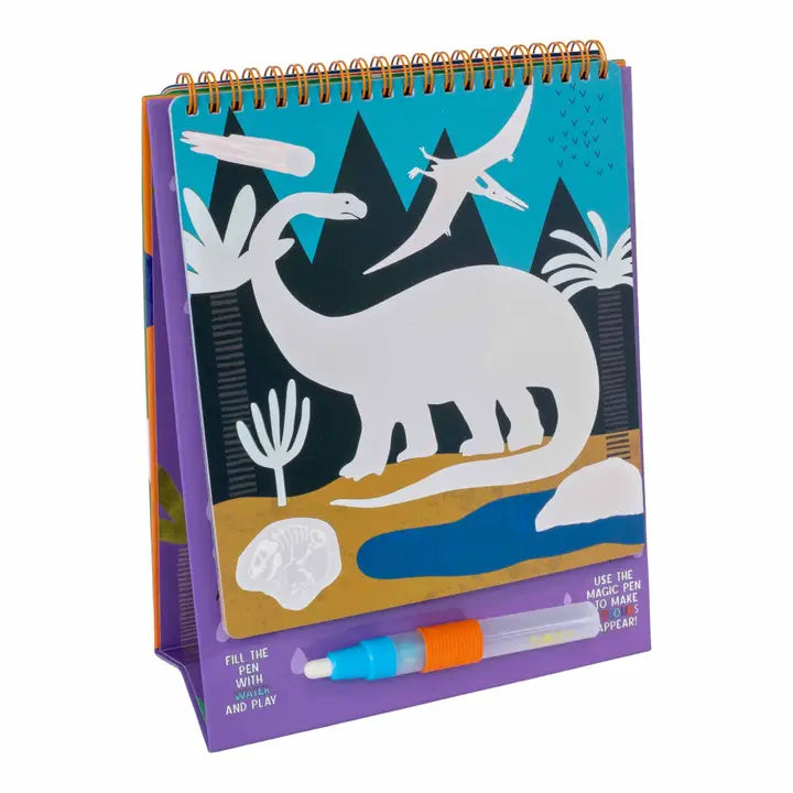 Spiral-bound water-reveal activity book depicting a prehistoric dinosaur landscape with a large white sauropod silhouette, jagged black mountains, and a blue and orange refillable water pen