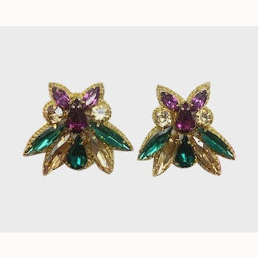 Vintage costume jewelry earrings featuring a pair of gold-tone clusters on a neutral background with vibrant purple teardrop crystals, emerald green marquise stones, and shimmering champagne accents