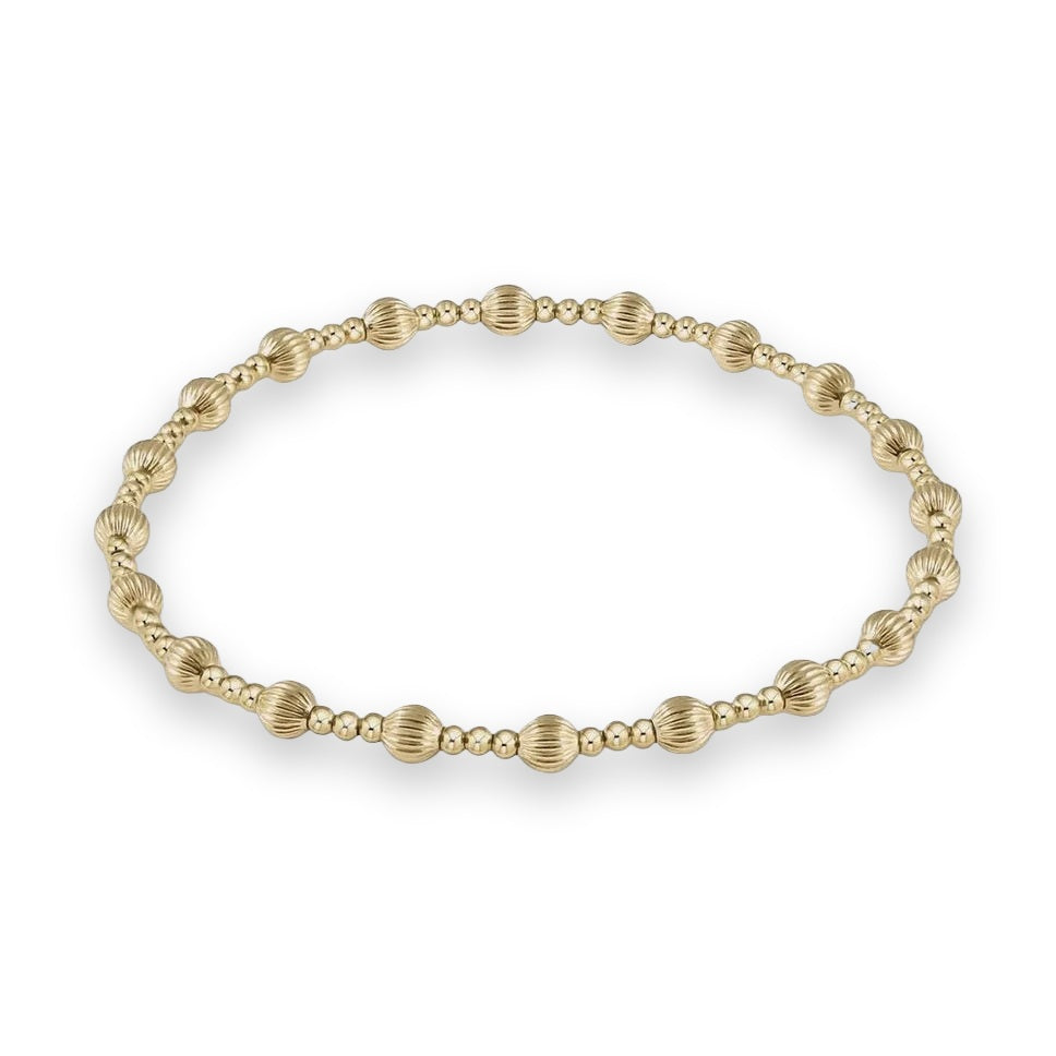 Gold beaded bracelet featuring alternating polished smooth spherical beads and larger vertically ridged scalloped beads centered on a light neutral background