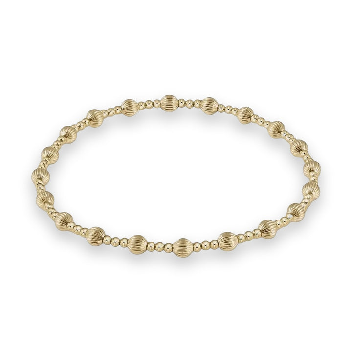 Gold beaded bracelet featuring alternating polished smooth spherical beads and larger vertically ridged scalloped beads centered on a light neutral background