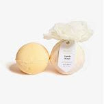 Product photography of two round pale yellow bath bombs on a white studio background with one wrapped in decorative ruffled white paper and featuring a vanilla honey label tag