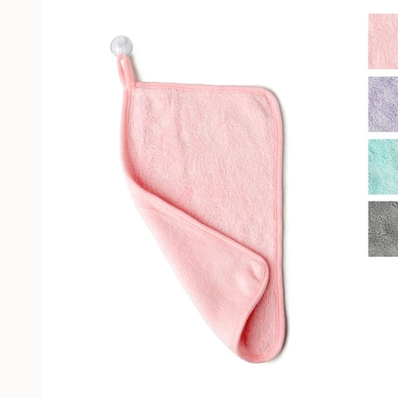 Product photograph of a pink microfiber towel hanging from a white suction cup on a plain background featuring a plush texture, small hanging loop, and color swatches in purple, mint, and grey