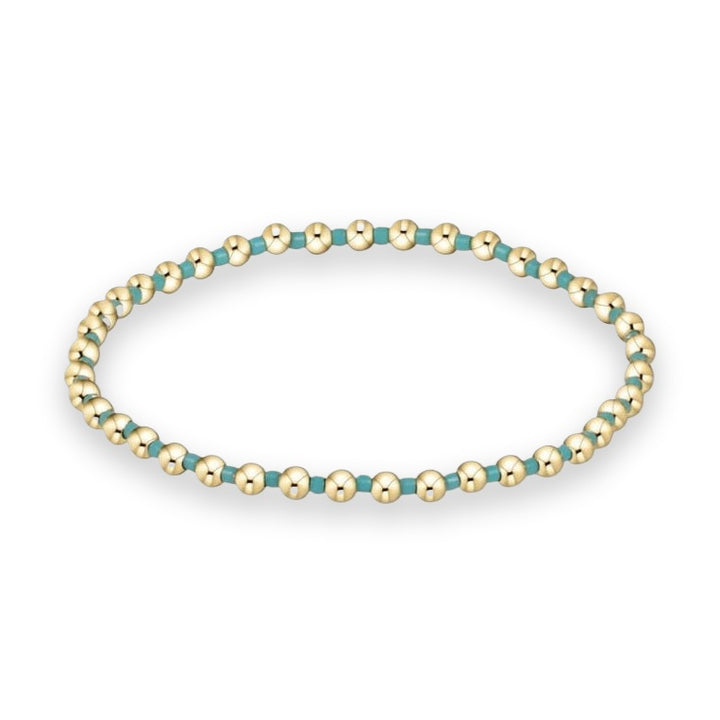 Handcrafted jewelry, a beaded gold and turquoise bracelet featuring polished yellow gold spheres and vibrant teal enamel spacers arranged in a continuous loop against a plain white background