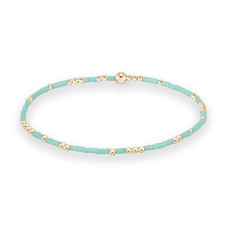 Handcrafted beaded jewelry bracelet featuring alternating turquoise seed beads and polished gold spheres with a larger central focal bead on a white background